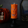 Orange LED Halloween candle with a pumpkin face on a black candlestick
