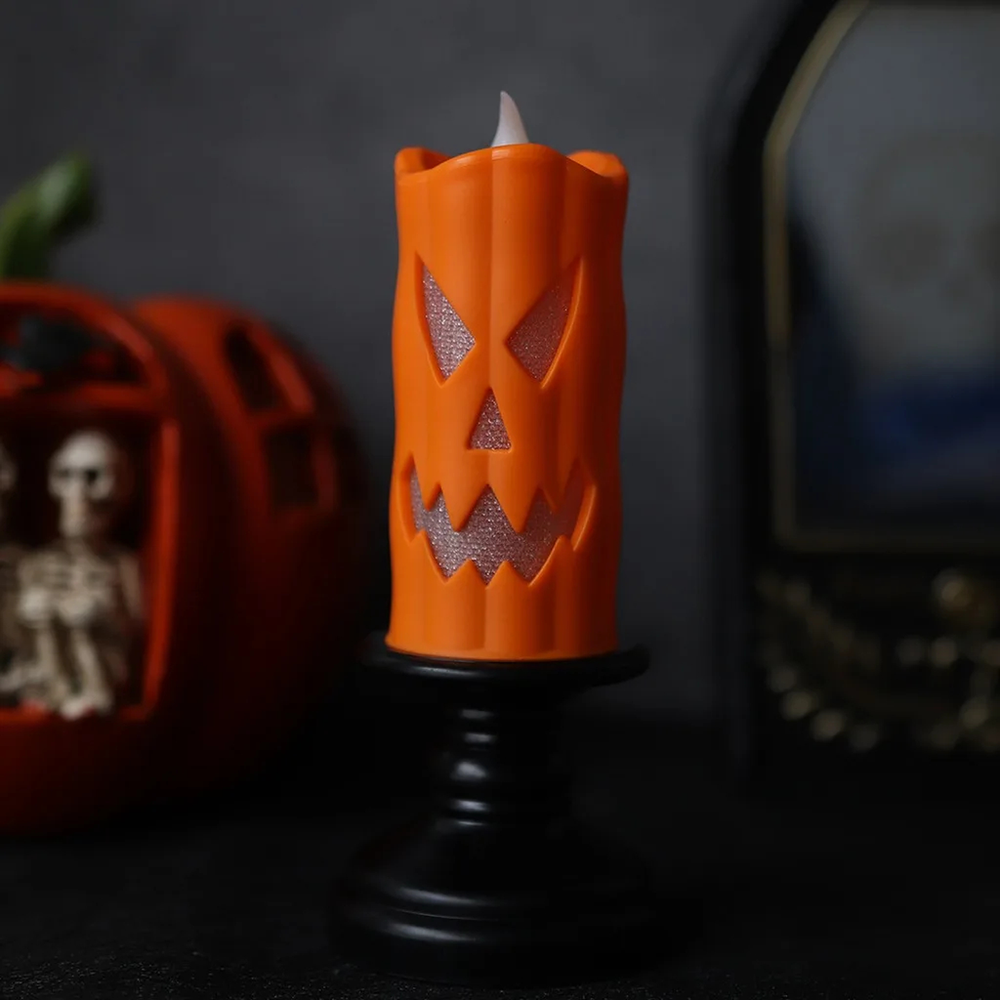 Orange LED Halloween candle with a pumpkin face on a black candlestick
