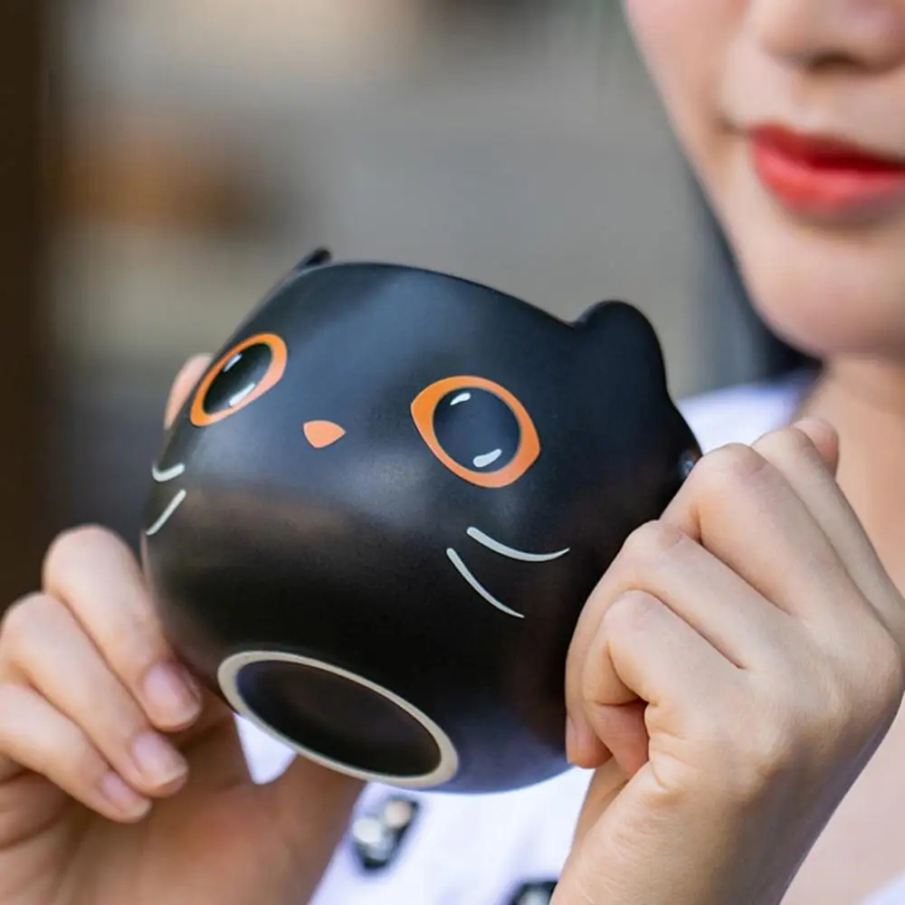 Black cat mug held in hand, seen from below